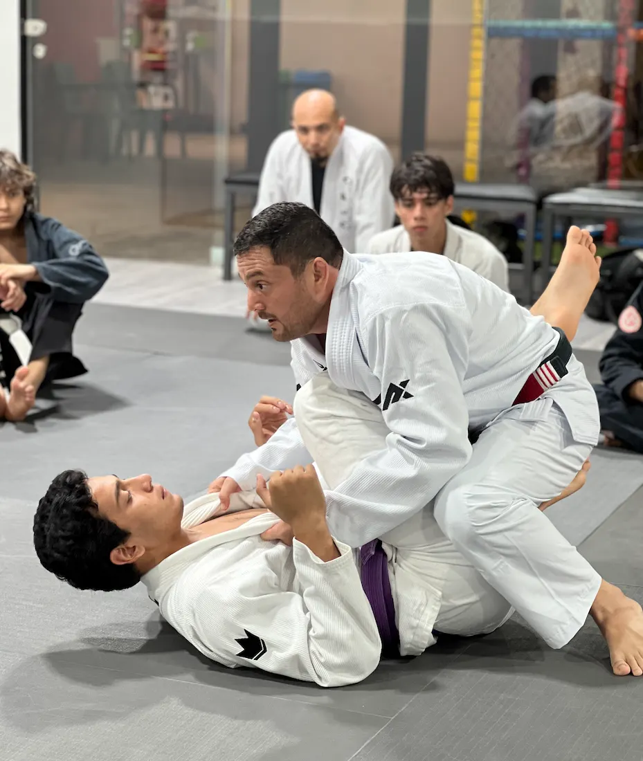 Profesor de APEX corrigiendo una posición de guardia a un alumno en el tatami